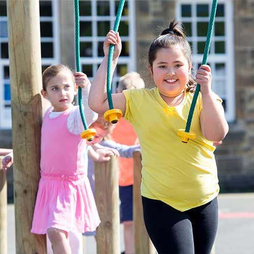 School children at break time playing on climbing frame