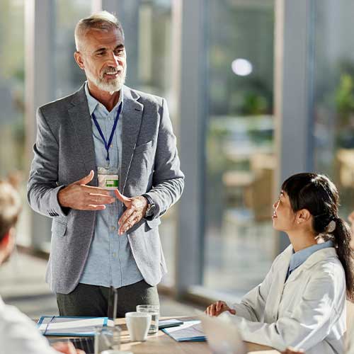 Happy senior administrator talking to group of medical experts during a meeting in hospital.