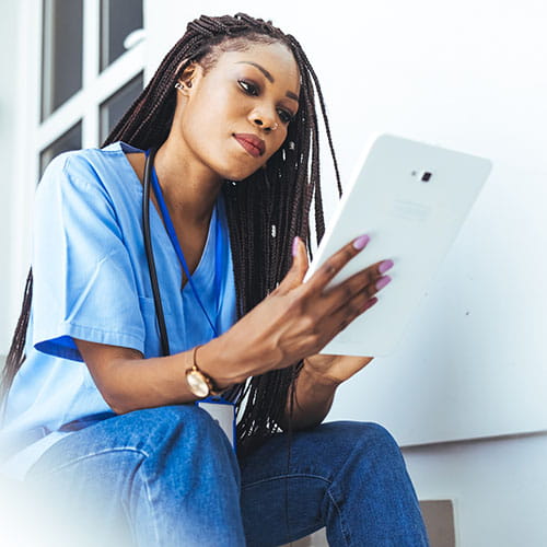 Woman reading a tablet while sitting on stairs in a hospital
