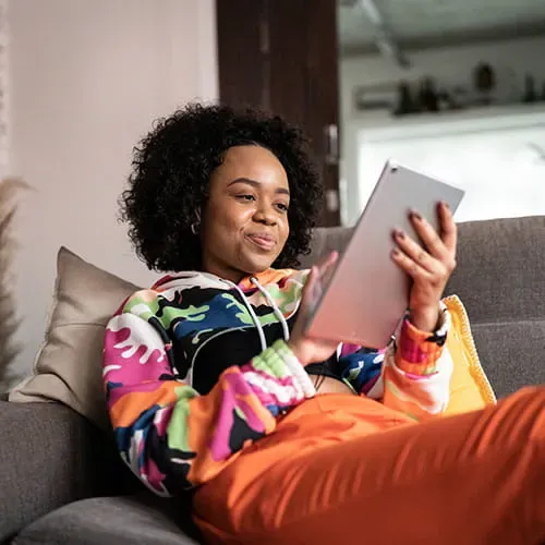 Woman sitting on a couch reading a tablet