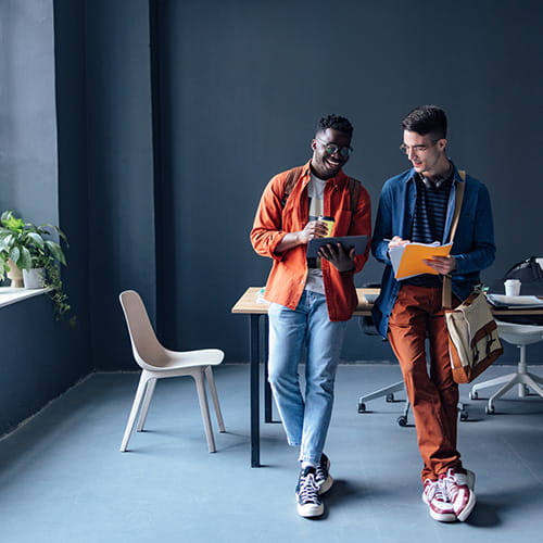 Two male students leaning on a table while looking at a tablet.