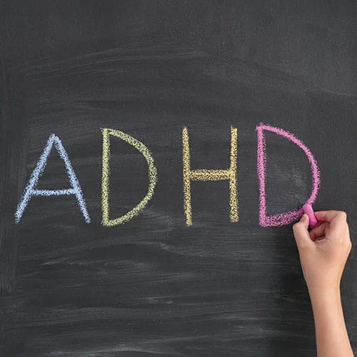 Person writing ADHD on a chalkbaord