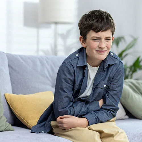 Child holding his stomach while sitting on a couch