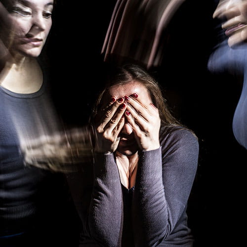Woman covering her face with schizophrenic illusions