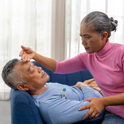Selective focus, Asian Caring senior woman touch on forehead and checking fever temperature with thermometer, looking at thermometer of husband's temperature, Old man lying on sofa with feel fever
