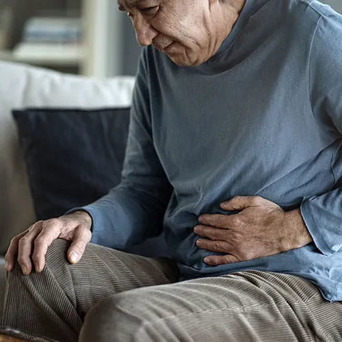 Older man leaned over holding his stomach