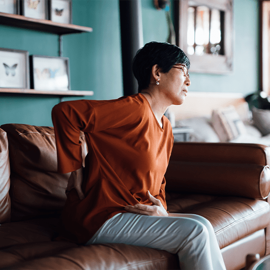 woman grimacing in back pain on couch