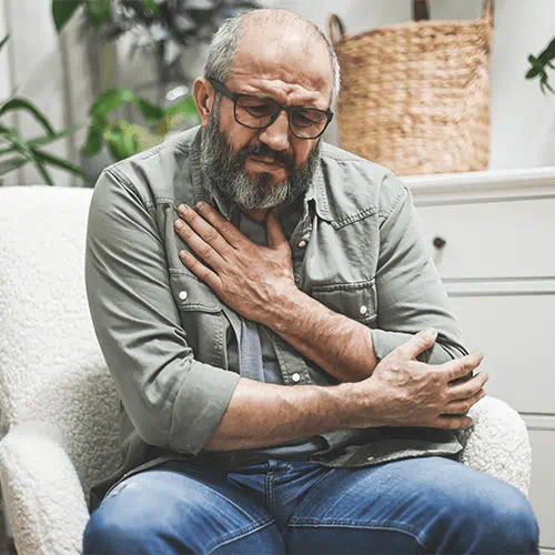 middle aged man holding his chest wincing in pain