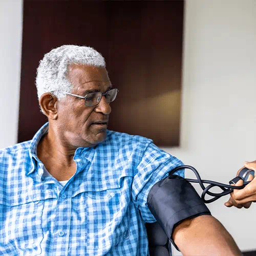 elderly man sitting and having his blood pressure taken manually