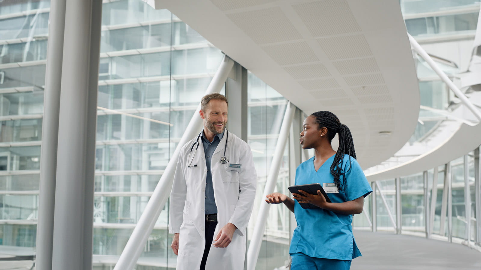 Medical professionals conversing while walking through a hospital bridge