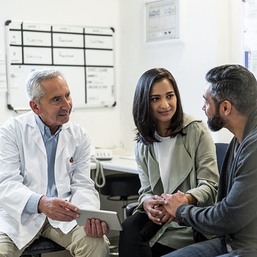 Doctor conversing with a mother and father in an office