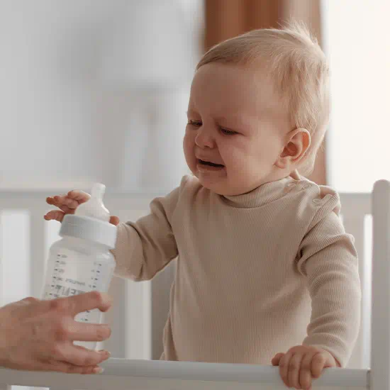 crying baby reaching for bottle