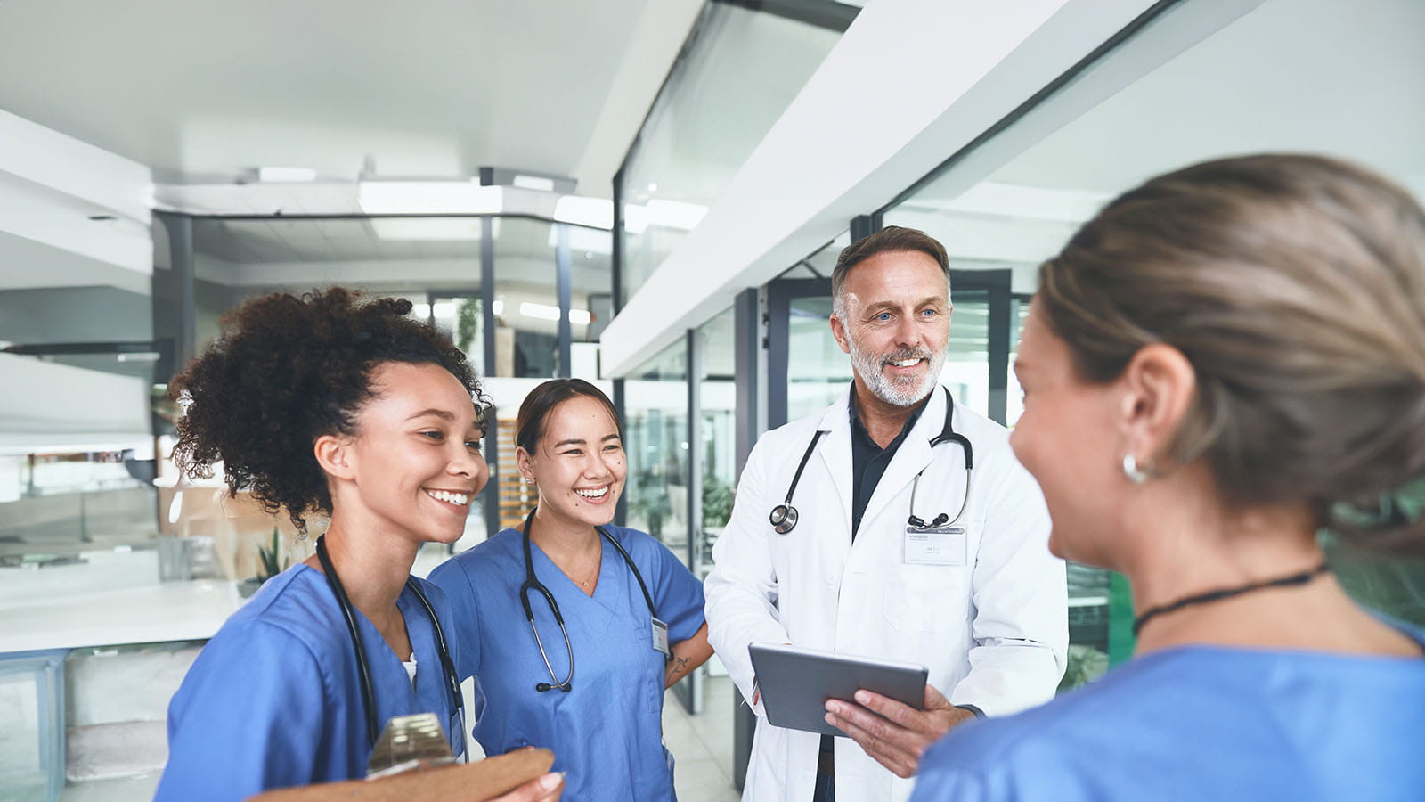 Group of nurses conversing with a doctor in a hospital hallway