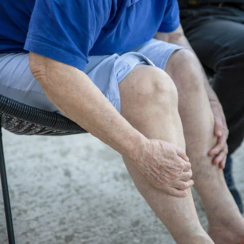 Person sitting in a chair holding their legs