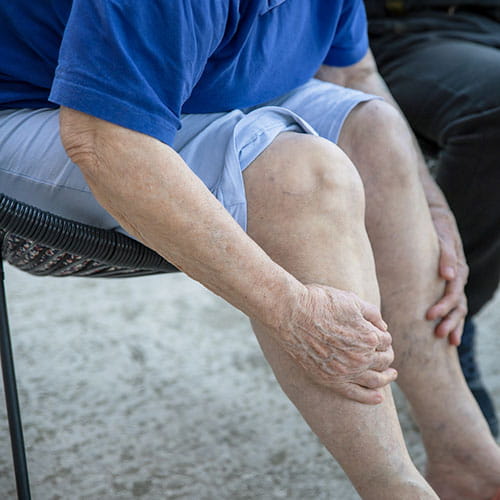 Person sitting in a chair holding their legs