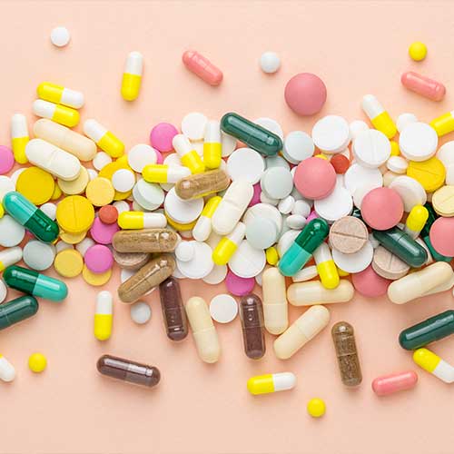 Many different pills on pink background. Prescription pills and vitamins. Flat lay and space for text