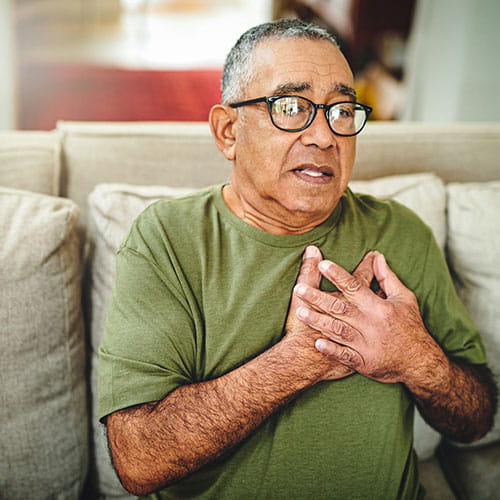 Man holding his chest on a couch