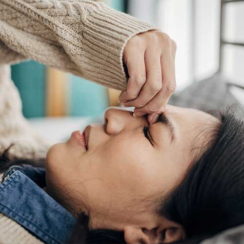 One woman, Japanese woman having headache while lying on bed in her bedroom at home.
