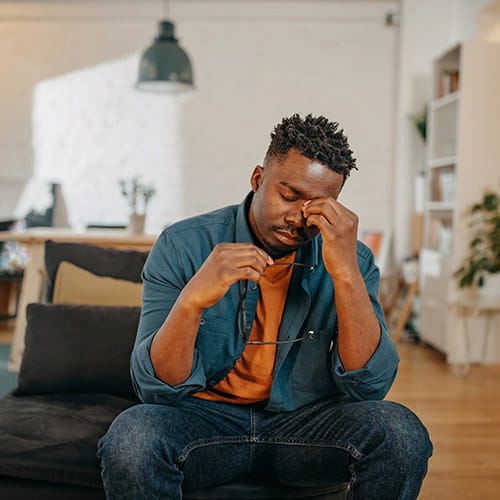 Man sitting on a couch with hand on face