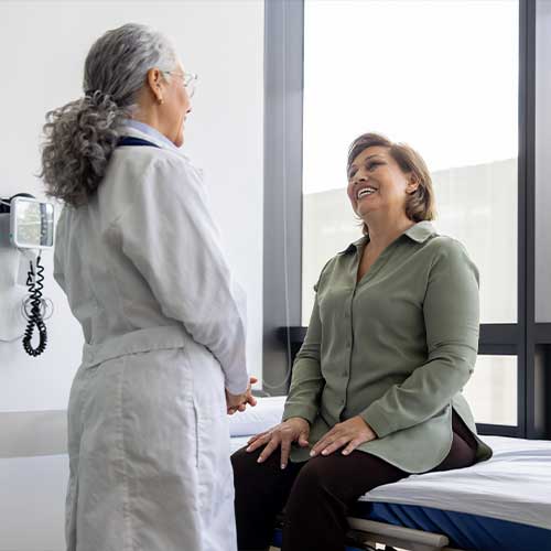 Mature Latin American woman talking to her doctor in the examination room - healthcare and medicine concepts