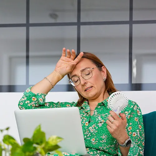 Woman putting her hand on her forehead in an office