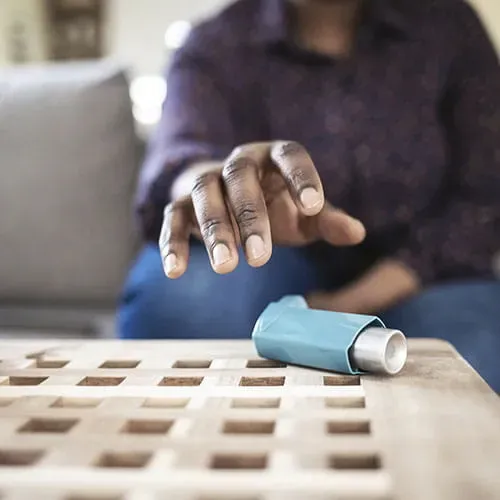 Person with their hand extended to grab an inhaler