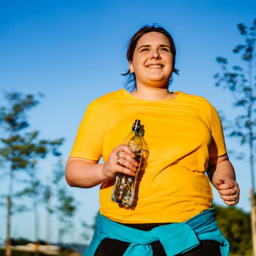 Woman jogging with a water bottle in hand
