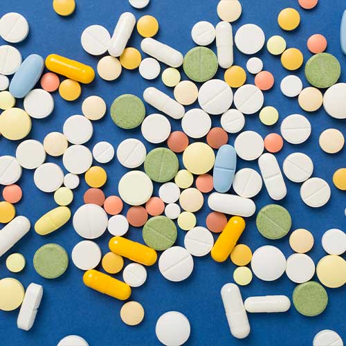 Different medical pills and capsules on color background, top view