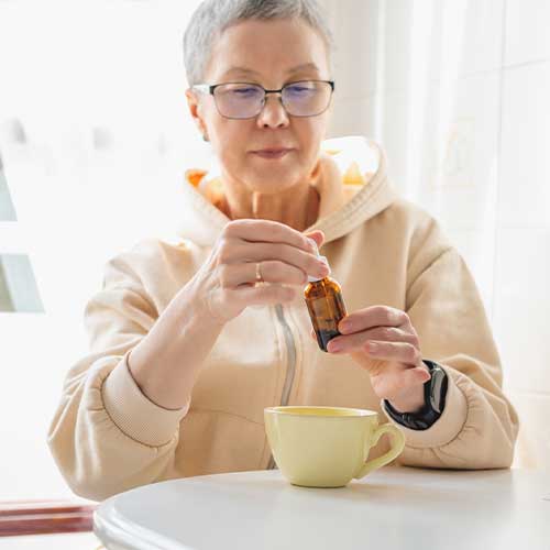 Mature woman taking cannabis oil in tea drink