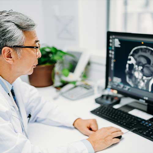 Asian senior male doctor is reading a CT scan at hospital.