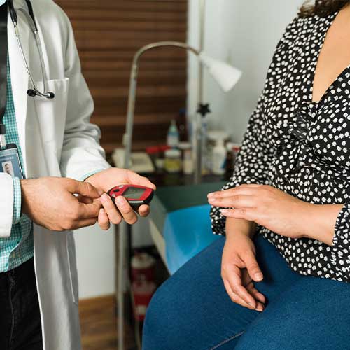Close up of a doctor checking the blood glucose with a monitor. Young woman with diabetes and obesity at a medical check-up