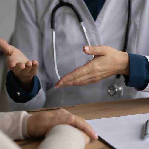 Doc consulting patient. Close up of young lady doctor in white coat talk to female patient explain diagnosis propose effective therapy. Focus on hands of woman qualified medic giving advices to client