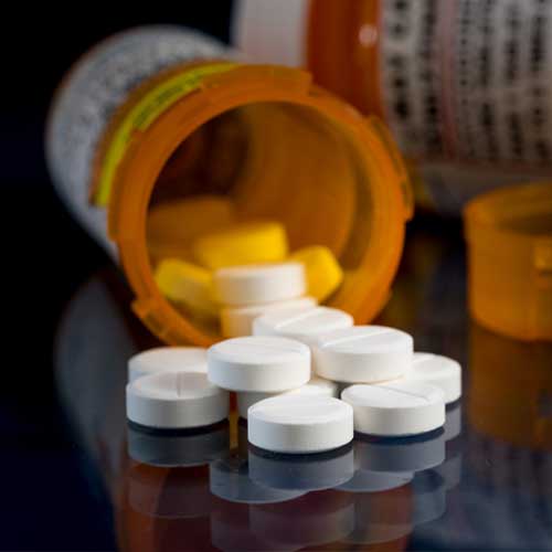 Prescription bottle for Oxycodone tablets and pills on glass table with reflections