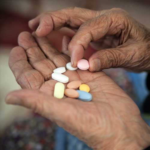 Close up of senior woman hand picking pill