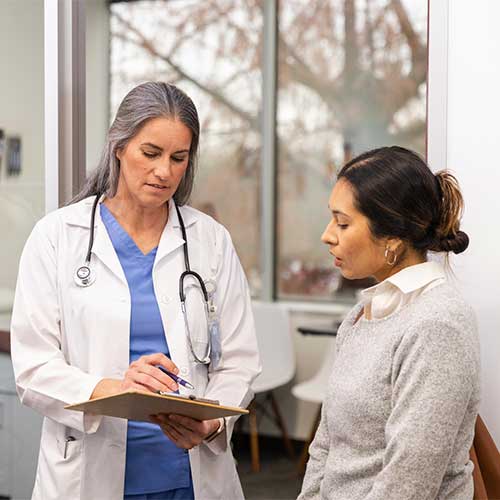 The serious mature adult female doctor gives the mid adult woman some bad news about the medical test results.