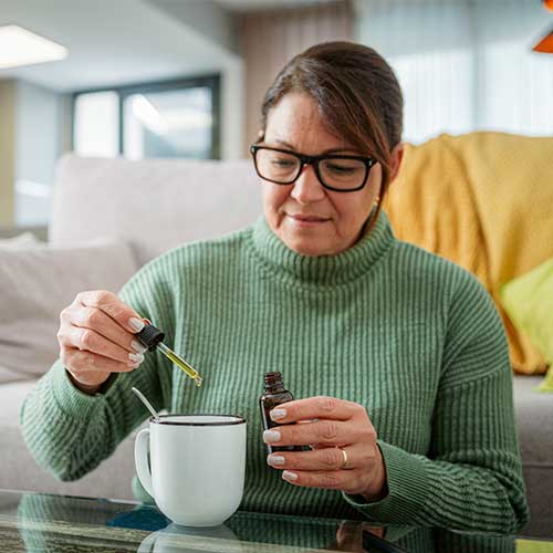 Portrait of a woman using a dropper to put medicine into a cup
