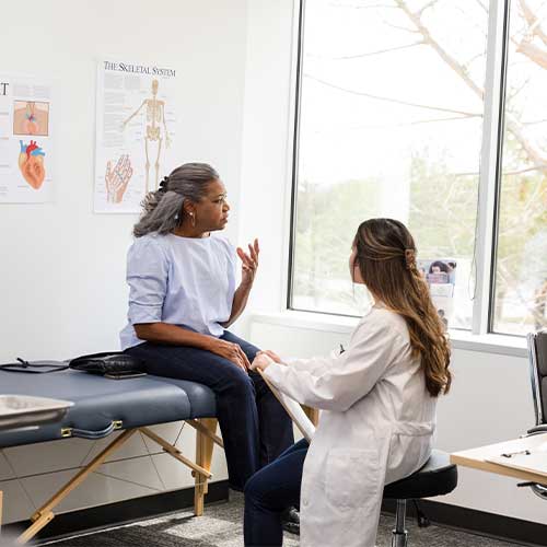 Mature woman patient talks with female doctor during medical consultation in office.