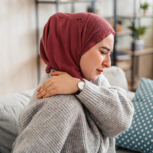 Woman reaching behind to soothe her back pain