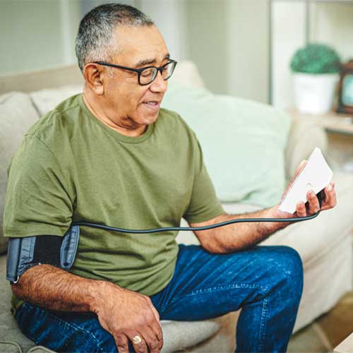 Shot of a senior man using a blood pressure monitor at home