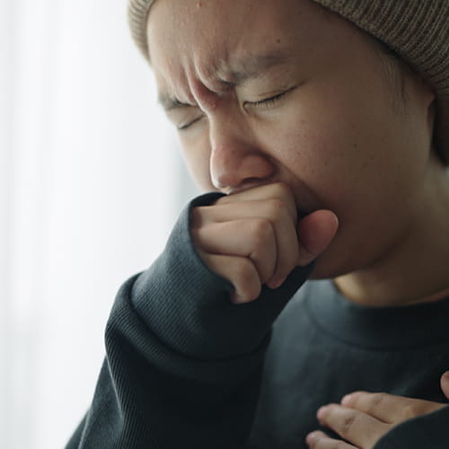 Person coughing into their fist.