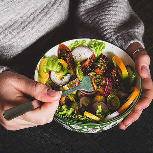 Woman holding bowl with a salad.