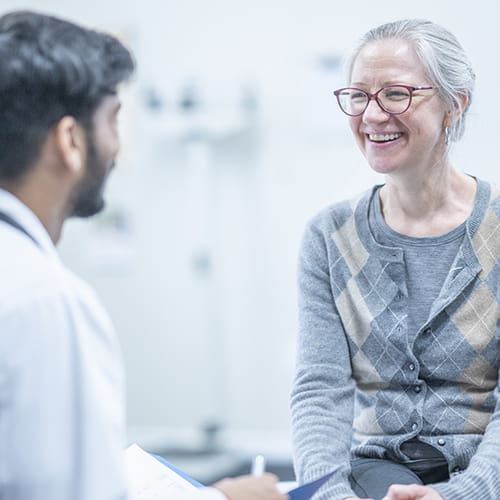 Smiling middle-aged woman talking with a clinician during an appointment.