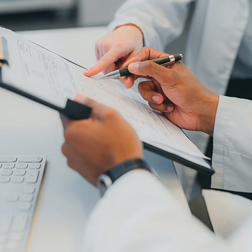 Two clinicians in white coats reviewing results on a clipboard.