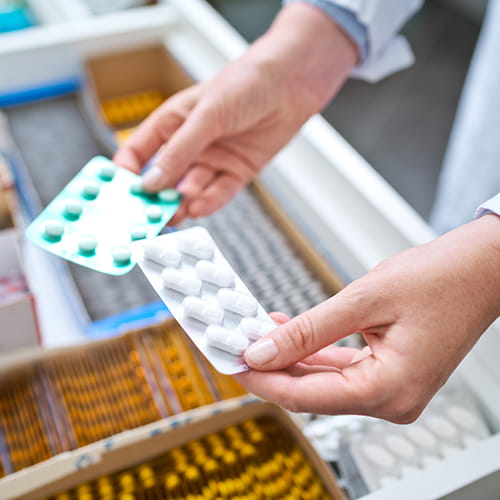 Pharmacist holding two pills blister packs of pills.