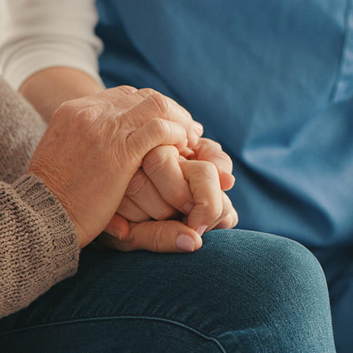 Nurse and senior woman holding hands.