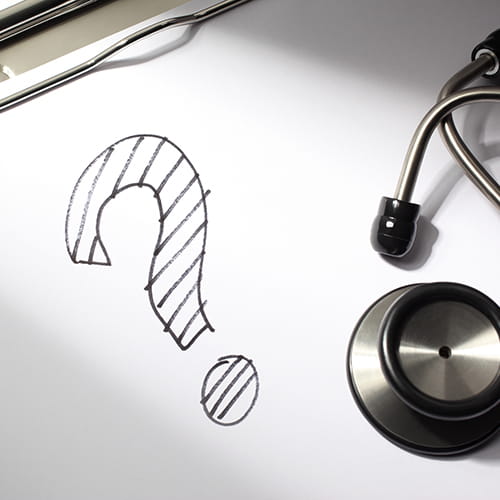 A question mark drawn on a doctor's clipboard next to a stethoscope.