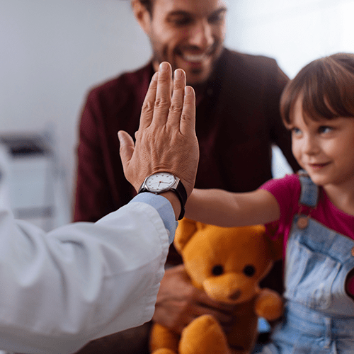 Pediatrician high fives a young girl.