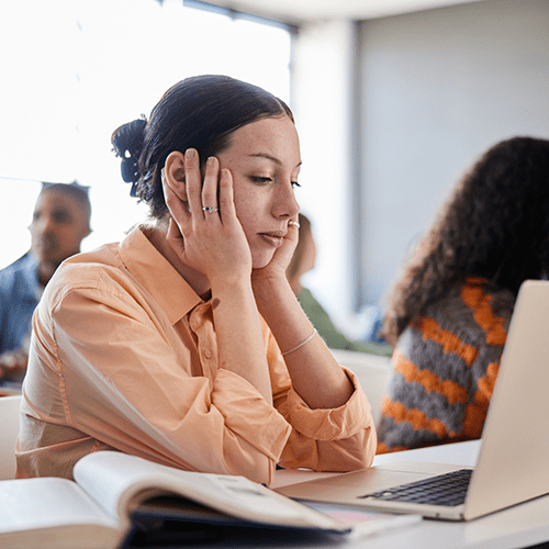 A distracted student looks at her laptop during class.