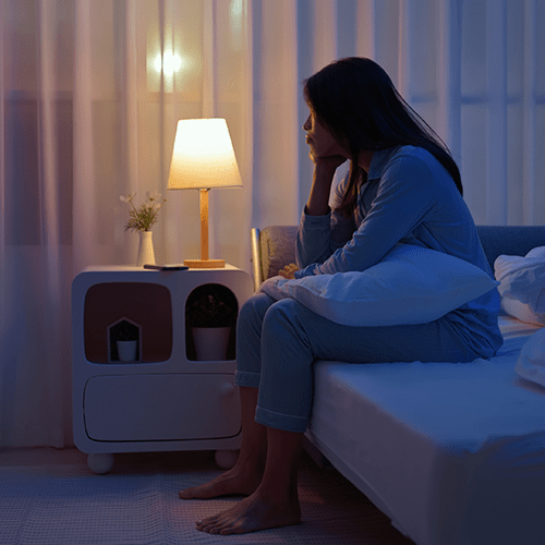 Woman sitting on a bed unable to sleep.