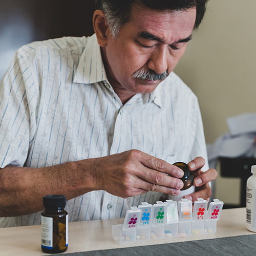 Man choosing pills from a plastic pill organizer